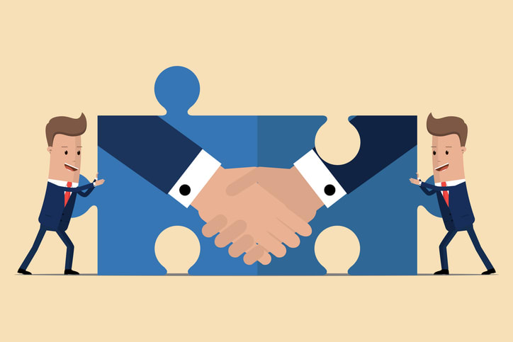 Two businessmen holding puzzle elements with a handshake